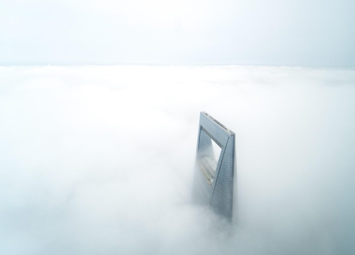直播平台评测中心编辑工作台实景，木质长桌上摊开多台笔记本与纸质资料，编辑正对照公开页面逐条核对直播平台信息，窗边自然光柔和铺陈，整体氛围安静克制